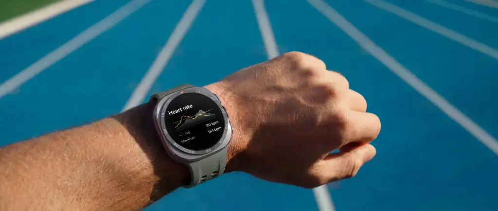 Primer plano de un smartwatch en la muñeca de una persona, mostrando el ritmo cardíaco en una pista azul. Indica 161 bpm promedio y 184 bpm máximo.