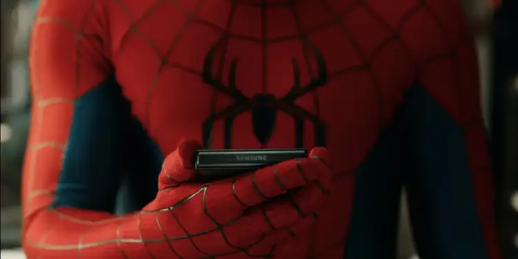 Persona con traje rojo y azul sosteniendo un smartphone plegable negro de la marca Samsung. El logo de Samsung es claramente visible.