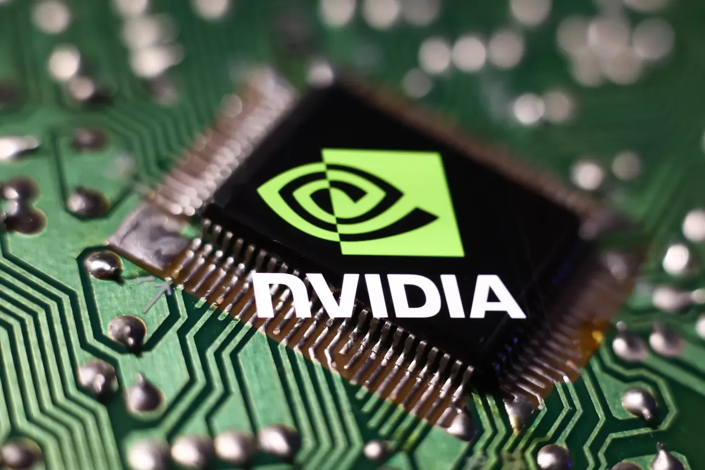 Primer plano de un microchip de NVIDIA montado sobre una placa de circuito impreso verde con componentes electrónicos.
