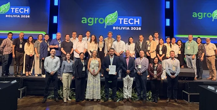 Amplio grupo de hombres y mujeres de negocios posando en el escenario del evento Agro Tech Bolivia 2026.