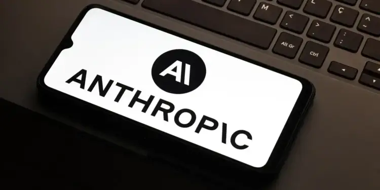 Teléfono inteligente mostrando el logotipo y nombre de Anthropic en su pantalla, colocado sobre una laptop.