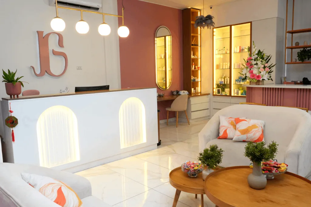 Recepción blanca iluminada con mostrador, sofás en el área de espera y estantes con productos en un negocio moderno.