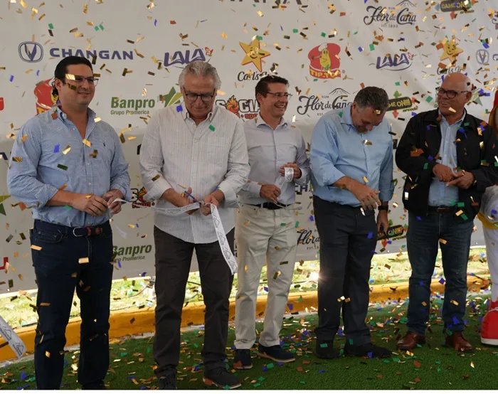 Cinco hombres de negocios cortando una cinta durante una ceremonia de inauguración con confeti cayendo