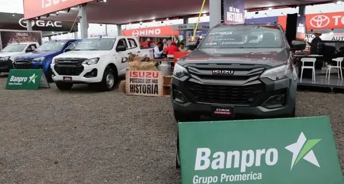 Exhibición de camionetas Isuzu en un evento comercial con carteles publicitarios de Banpro Grupo Promerica.