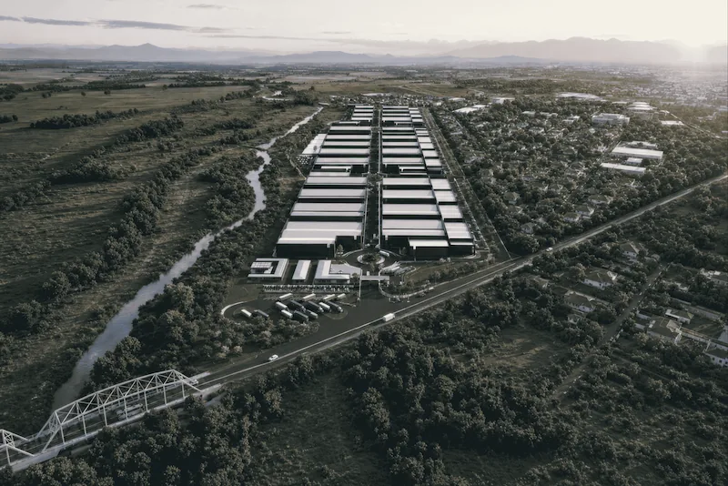Vista aérea de un gran complejo industrial y logístico con múltiples naves y camiones de carga.