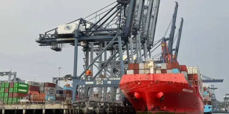 Gran barco de carga rojo, el 'Polar Colombia', atracado en un puerto con múltiples grúas portuarias y pilas de contenedores de envío.