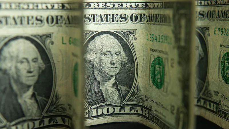Primer plano de varios billetes de un dólar estadounidense, mostrando el retrato de George Washington y el texto 'STATES OF AMERICA' y 'ONE DOLLAR'.