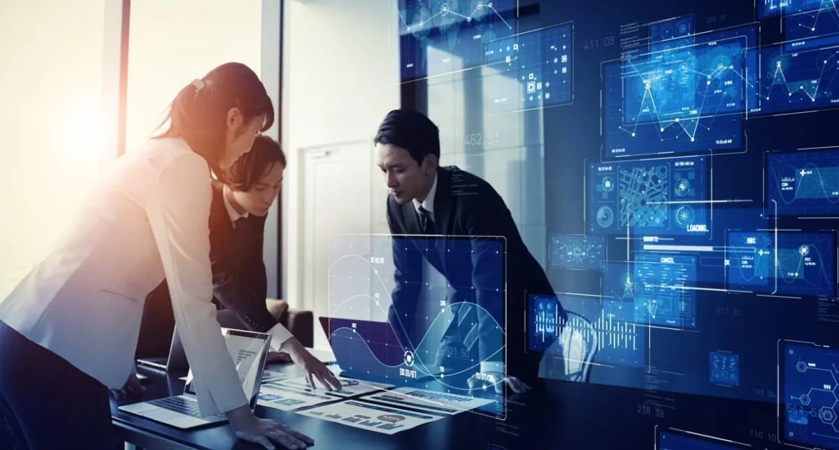 Tres profesionales analizando gráficos digitales y datos financieros sobre una mesa de reuniones.