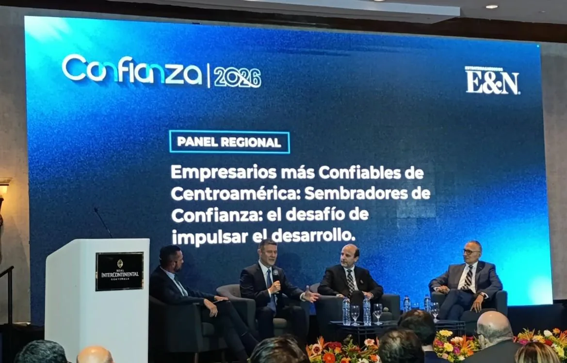 Cuatro empresarios en un panel de discusión sobre confianza y desarrollo en Centroamérica, con una pantalla mostrando 'Confianza 2026' y el tema del evento.
