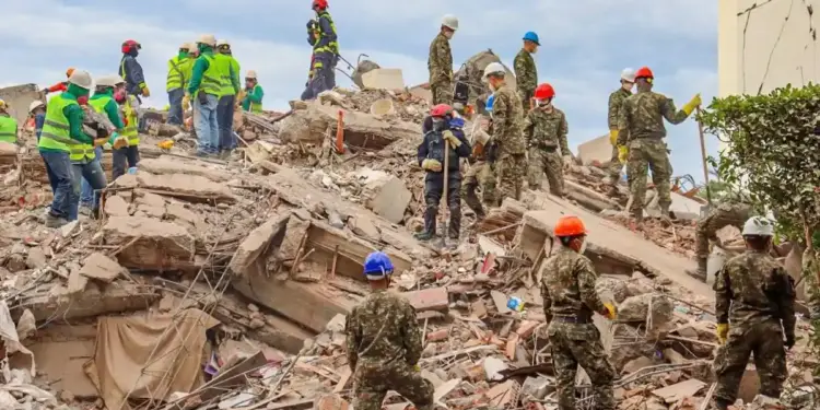 Personal de rescate y voluntarios con cascos trabajando entre los escombros de un edificio derrumbado.