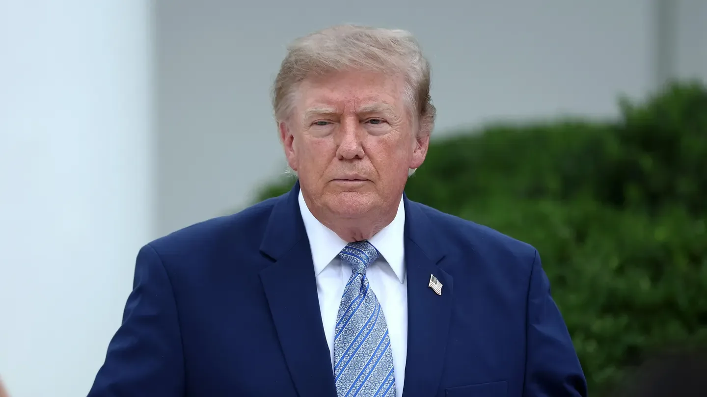 Retrato de medio cuerpo de Donald Trump vistiendo traje azul marino, camisa blanca y corbata azul con patrón.
