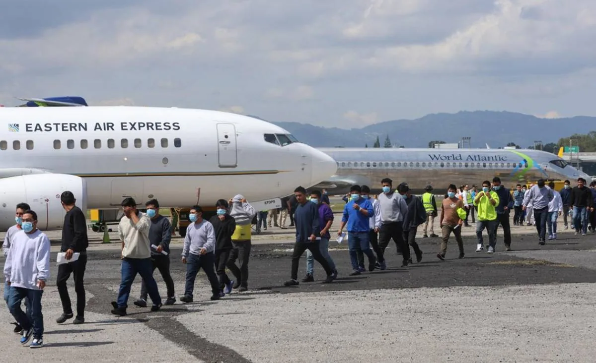 Grupo de personas caminando en la pista de un aeropuerto frente a aviones de Eastern Air Express y World Atlantic.