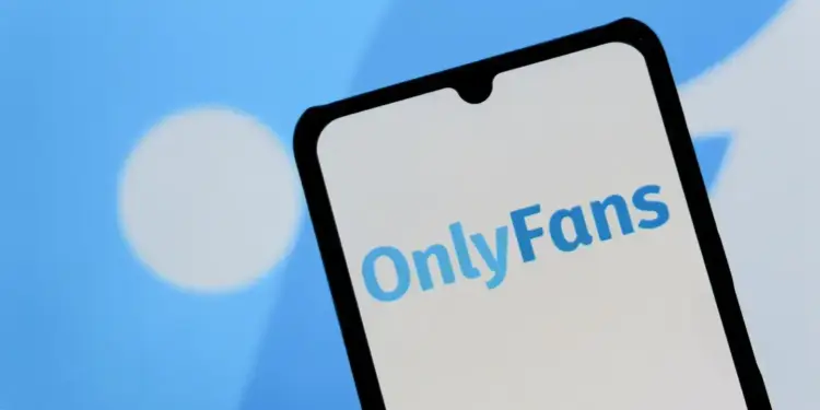 Logotipo azul de OnlyFans visible en la pantalla blanca de un smartphone con fondo azul difuminado.