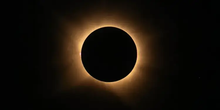 Imagen de un eclipse solar total mostrando la corona brillante del sol alrededor de la luna oscura. El cielo es negro.