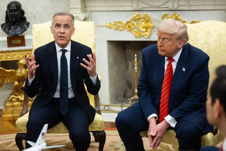 Dos hombres con traje azul conversan en una oficina elegante frente a una chimenea decorada.