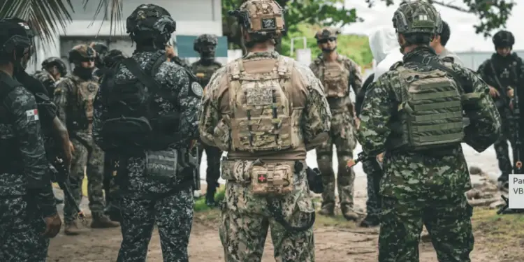 Grupo de fuerzas especiales uniformados con equipo táctico y cascos en un área exterior al aire libre.