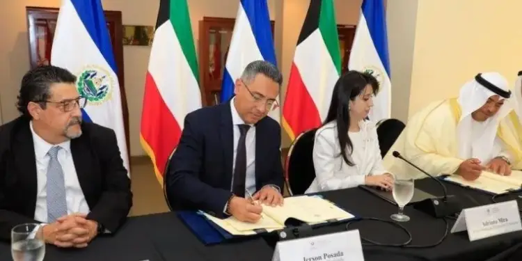 Funcionarios en mesa con banderas firmando documentos oficiales en reunión diplomática.