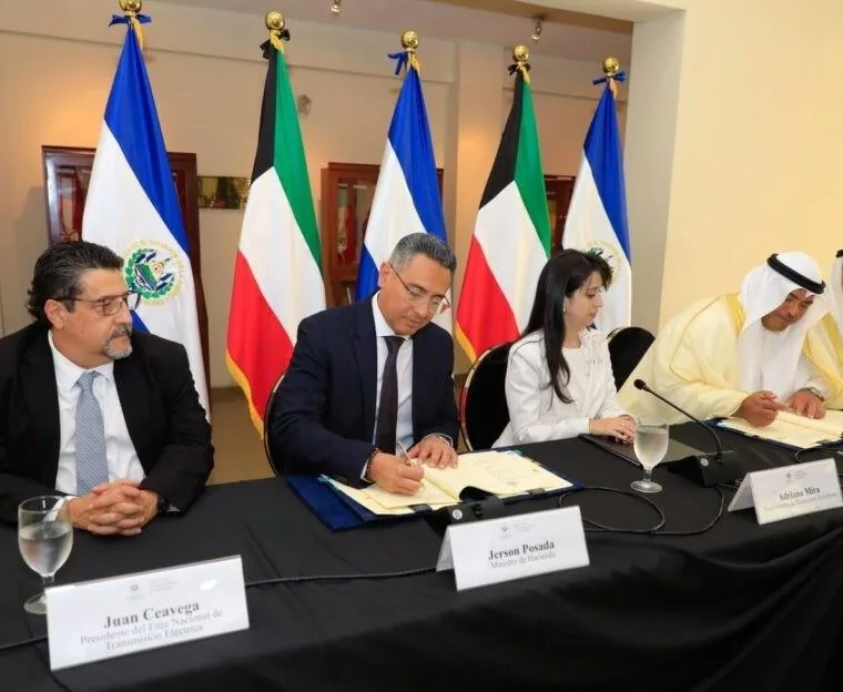 Funcionarios en mesa con banderas firmando documentos oficiales en reunión diplomática.