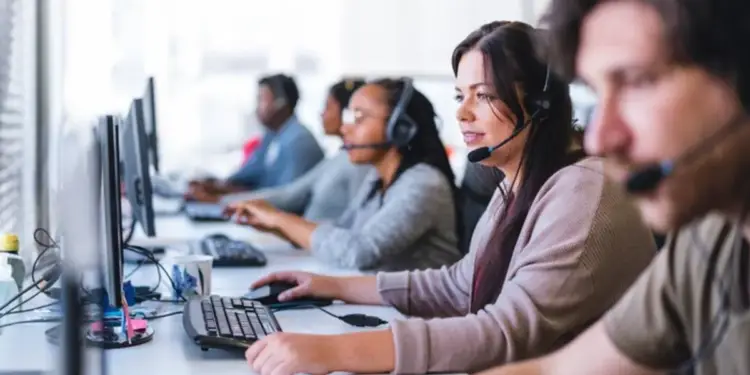 Grupo de operadores con auriculares y computadoras trabajando en un centro de llamadas