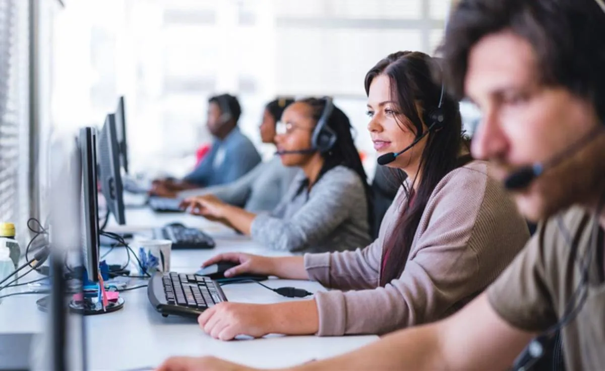 Grupo de operadores con auriculares y computadoras trabajando en un centro de llamadas