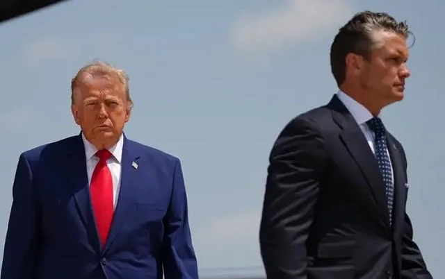 Dos hombres con traje formal y corbata caminando al aire libre bajo el cielo despejado.