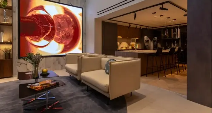 Sala de estar moderna con sofás beige, mesa de centro y una gran pantalla con arte abstracto rojo.