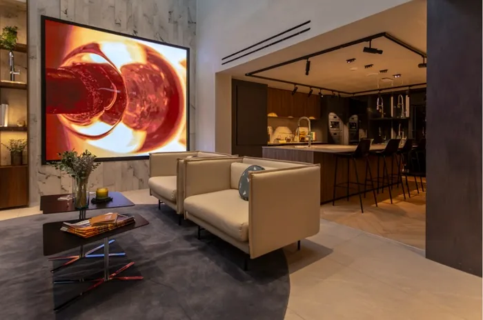 Sala de estar moderna con sofás beige, mesa de centro y una gran pantalla con arte abstracto rojo.