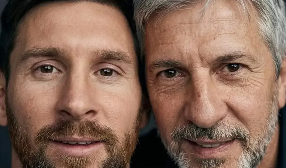 Primer plano de dos hombres, uno joven con cabello oscuro y barba, y otro mayor con cabello y barba grises, ambos sonriendo ligeramente.