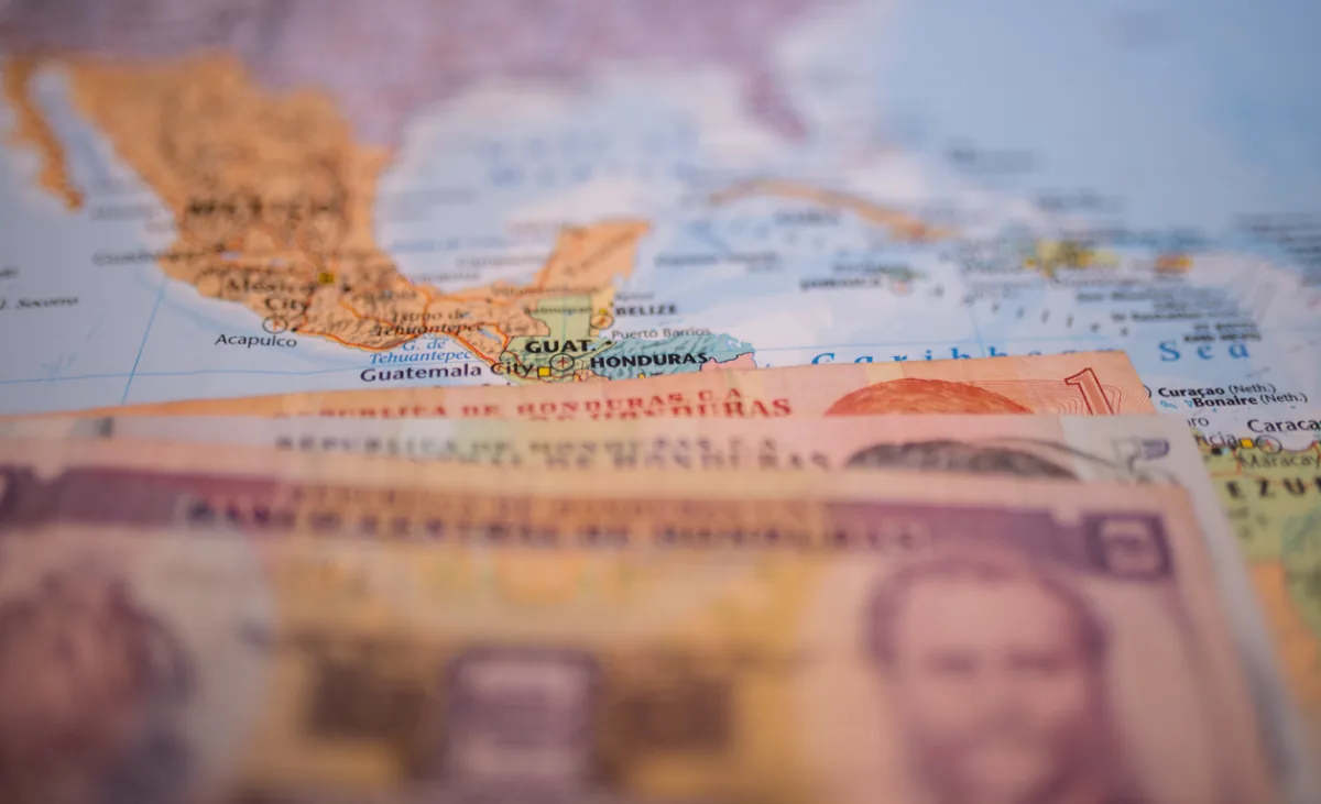 Billetes de Lempiras hondureños sobre un mapa de Centroamérica, destacando Honduras, Guatemala y México. Enfoque en economía regional.