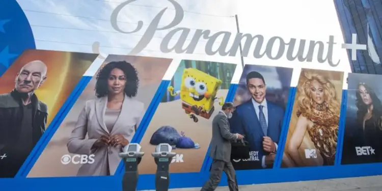 Gran valla publicitaria de Paramount+ mostrando personajes de sus programas. Un hombre de negocios con mascarilla pasa caminando.