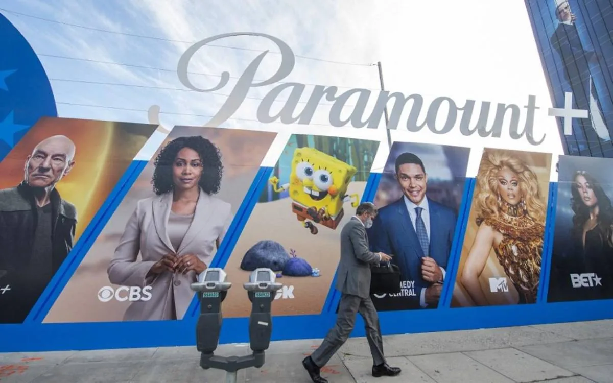Gran valla publicitaria de Paramount+ mostrando personajes de sus programas. Un hombre de negocios con mascarilla pasa caminando.