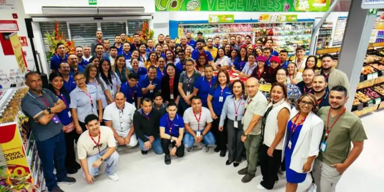 Fotografía grupal de un numeroso equipo de empleados en el pasillo de un supermercado con sección de vegetales.