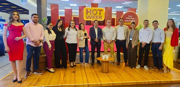 Grupo de doce profesionales, seis hombres y seis mujeres, posando en un evento comercial con letreros de 'HOT WEEK' y 'Las Ofertas'.
