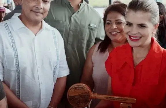 Grupo de personas sonrientes sosteniendo un reconocimiento de madera con placa y mazo en un evento profesional.