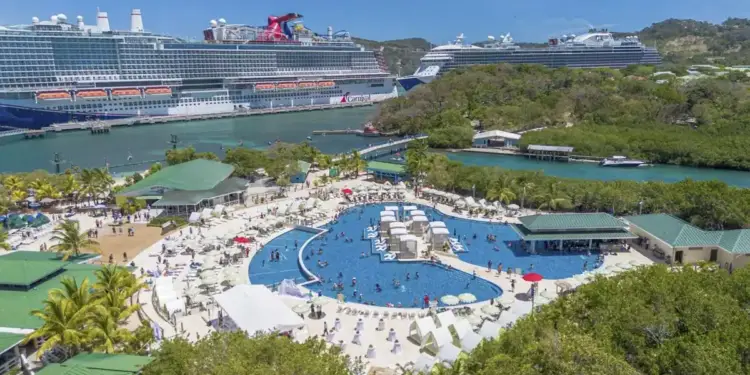 Vista aérea de un complejo turístico tropical con una gran piscina y grandes cruceros atracados en el puerto.