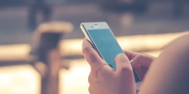 Persona sosteniendo un teléfono móvil inteligente con pantalla táctil en uso.