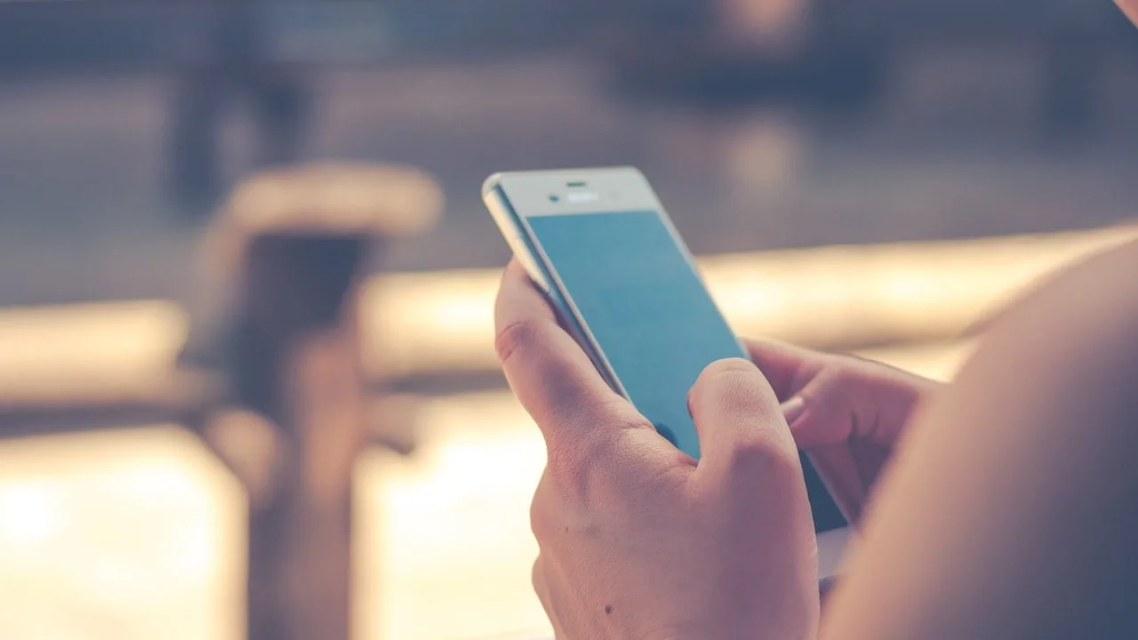 Persona sosteniendo un teléfono móvil inteligente con pantalla táctil en uso.