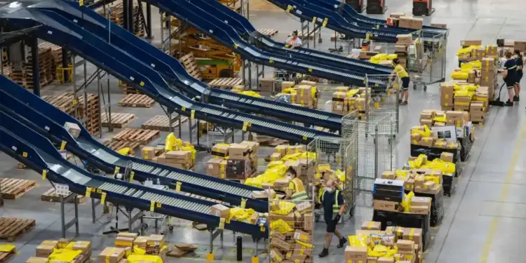 Vista aérea de un centro de distribución industrial con cintas transportadoras y trabajadores organizando paquetes.