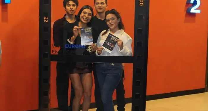 Cuatro jóvenes sonrientes posan juntos dentro de un marco decorativo con diseño de película cinematográfica en un pasillo.