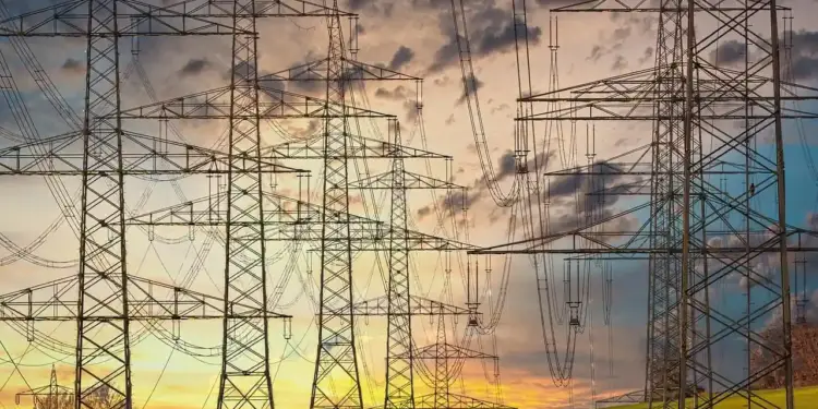 Múltiples torres de alta tensión y tendido eléctrico sobre un campo verde al atardecer.