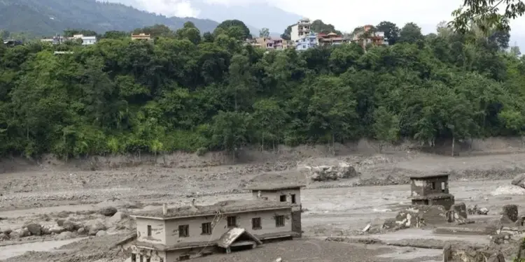 Viviendas y estructuras dañadas por un aluvión de lodo y sedimentos en una zona afectada por desastres naturales.