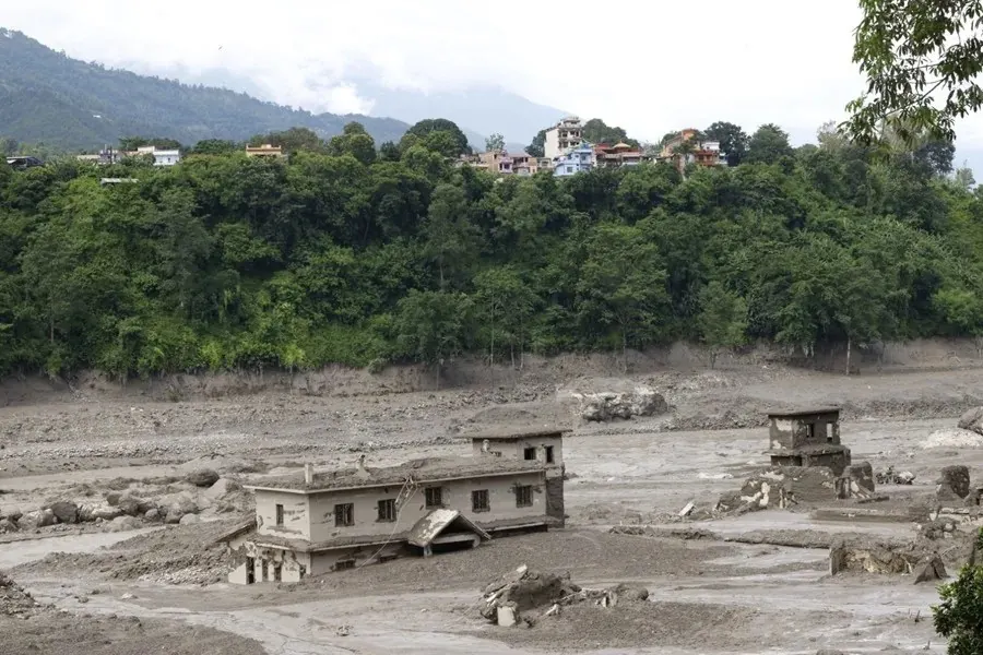 Viviendas y estructuras dañadas por un aluvión de lodo y sedimentos en una zona afectada por desastres naturales.
