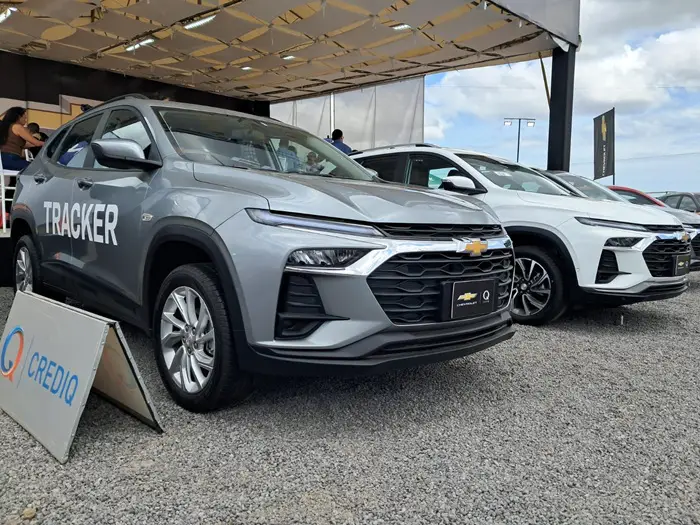 Dos SUV Chevrolet, una gris Tracker y una blanca, exhibidas al aire libre con un cartel de financiamiento CREDIQ en primer plano.