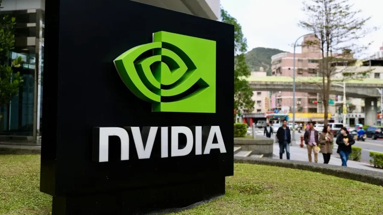 Gran letrero negro con el logotipo verde y el nombre en blanco de NVIDIA en una acera urbana al aire libre.