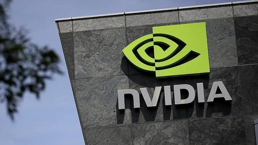 Logotipo verde y letras plateadas de Nvidia en la fachada de piedra de un edificio corporativo.