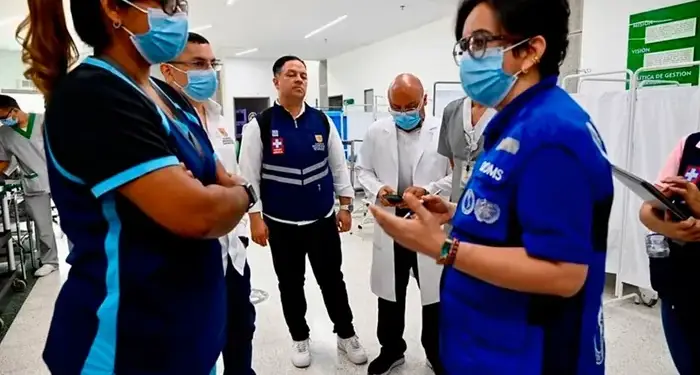 Varios profesionales de la salud con mascarillas y uniformes se reúnen en un espacio institucional, dialogando sobre gestión.