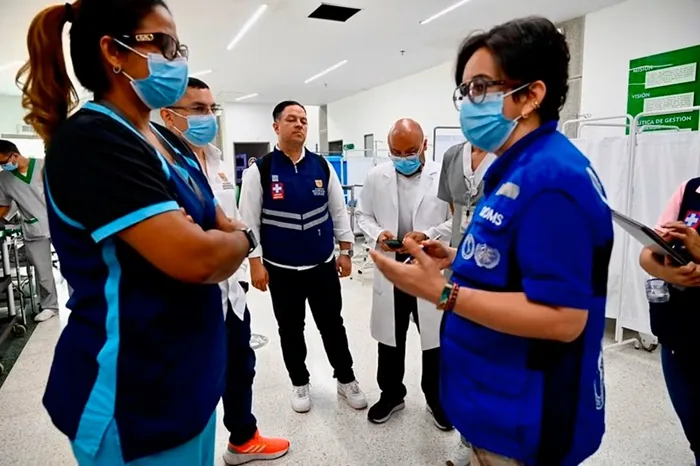 Varios profesionales de la salud con mascarillas y uniformes se reúnen en un espacio institucional, dialogando sobre gestión.