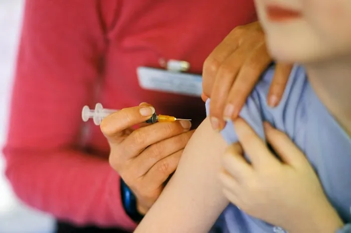 Personal médico aplicando una inyección con jeringa en el brazo de un paciente.