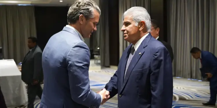 Dos hombres con traje formal estrechándose la mano en un salón de eventos corporativo