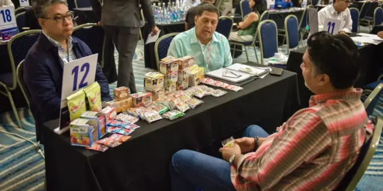 Hombres sentados en una mesa con muestras de productos durante una conferencia o feria de negocios.